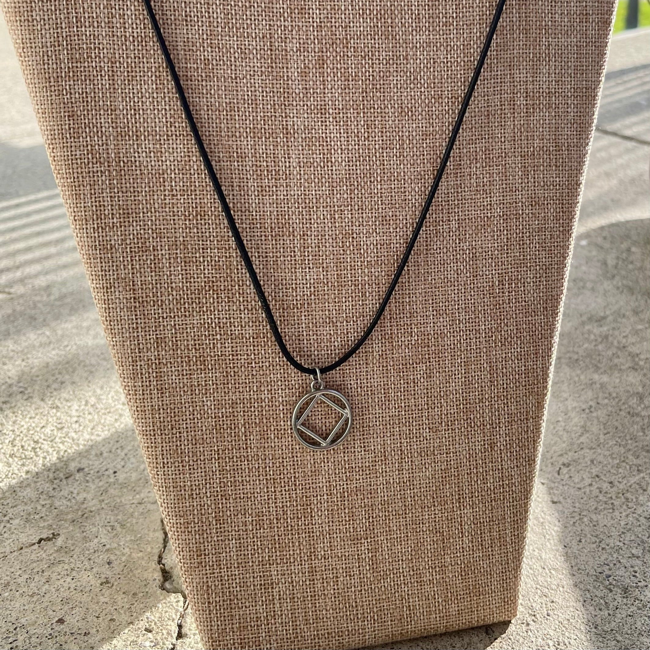 Necklace with a narcotics anonymous pendant on a brown surface