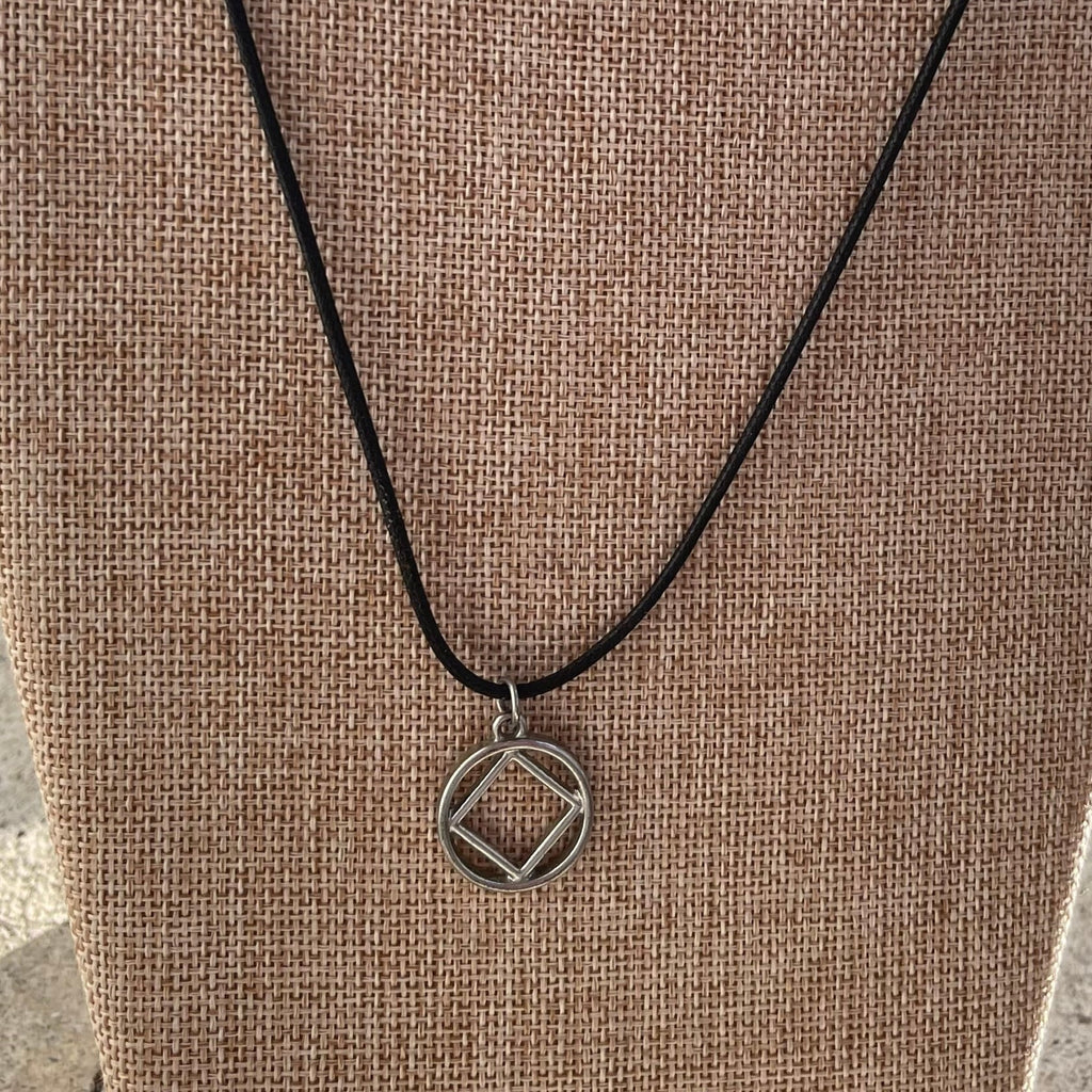 Closeup image of NA Charm Necklace on fabric background