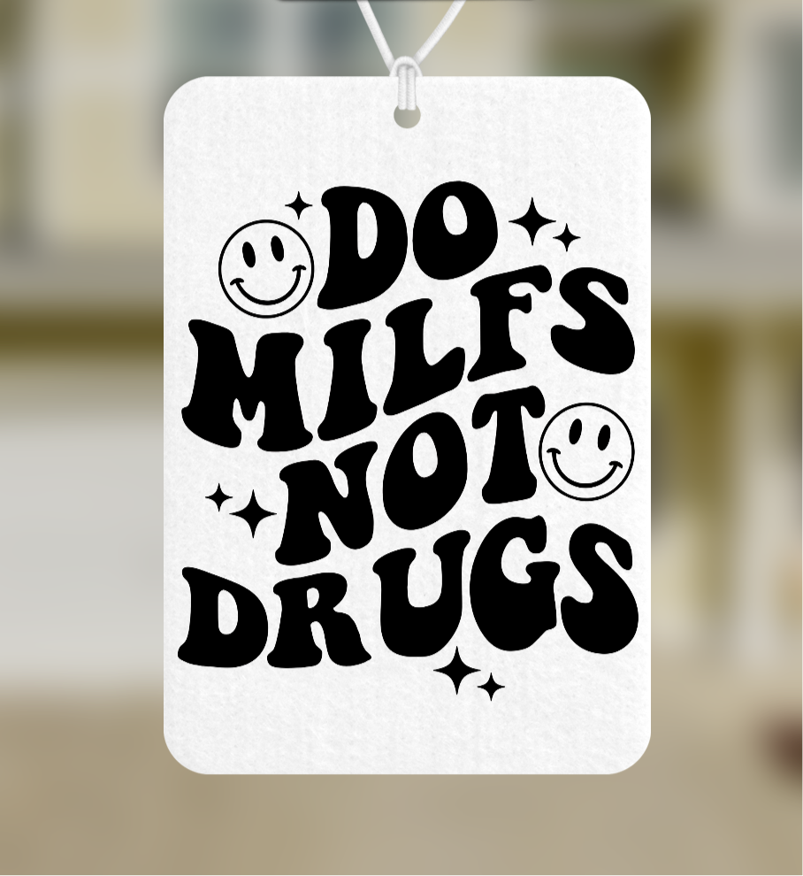 This image displays a bold and playful car air freshener featuring the phrase "DO MILFS NOT DRUGS" in a fun, bold font, adorned with smiley faces and stars. The air freshener, measuring 2.