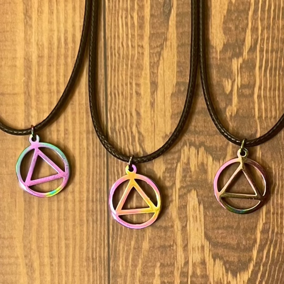 Three necklaces with triangle pendants on a wooden surface
